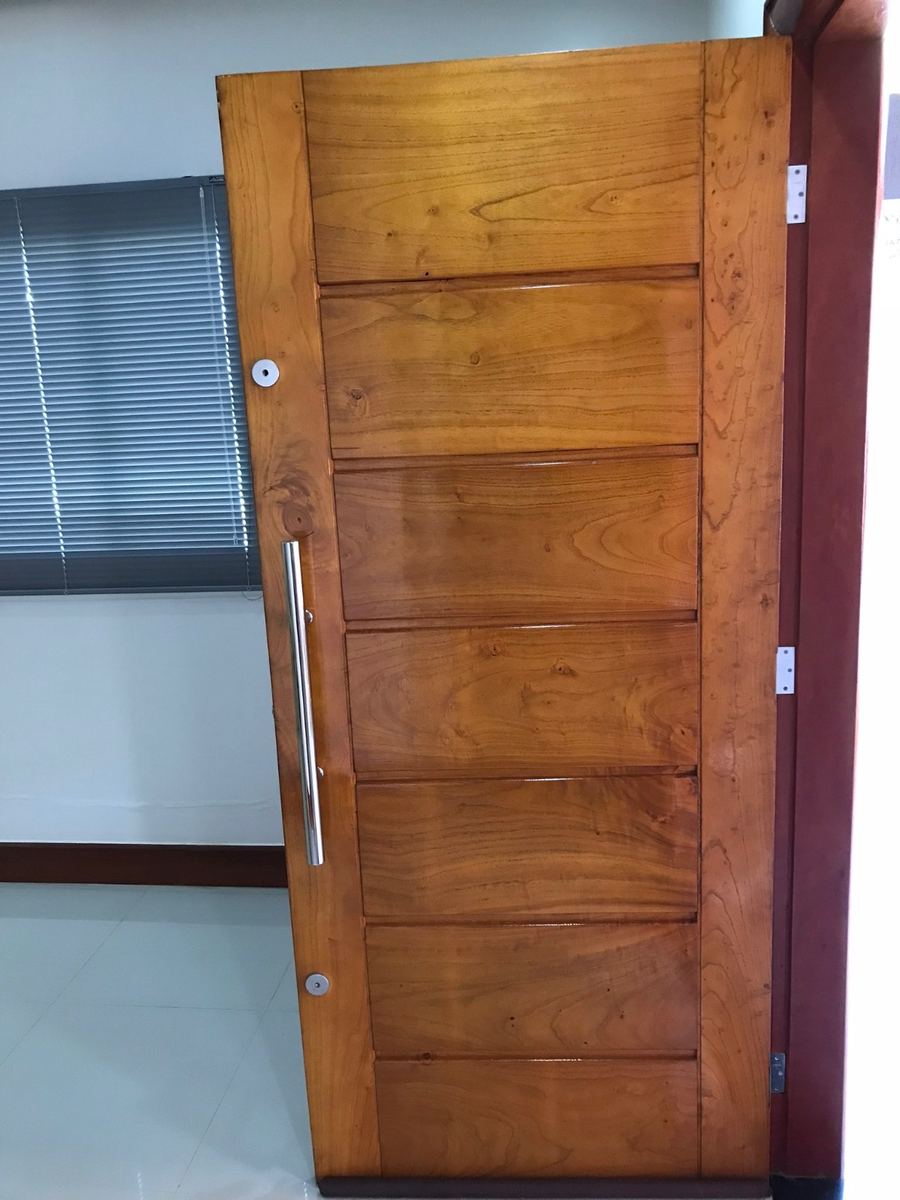 Porta de madeira maciça instalada com puxador em inox